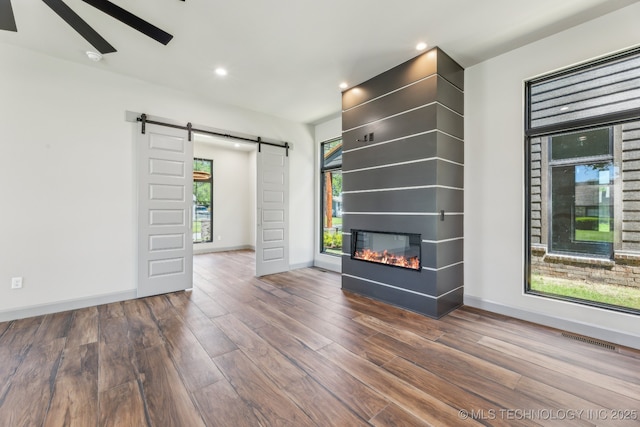 425 W Ft Worth St, Broken Arrow, OK 74012 - empty room featuring a barn door, wood finished floors, a glass covered fireplace, baseboards, and visible vents