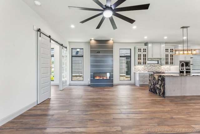 425 W Ft Worth St, Broken Arrow, OK 74012 - living room featuring a barn door, recessed lighting, dark wood-style floors, a ceiling fan, and a multi sided fireplace