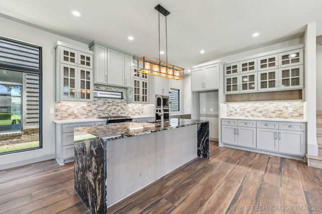 425 W Ft Worth St, Broken Arrow, OK 74012 - kitchen featuring stainless steel appliances, dark stone counters, tasteful backsplash, dark wood finished floors, and an island with sink