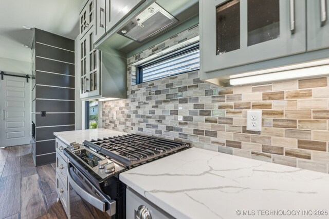 425 W Ft Worth St, Broken Arrow, OK 74012 - kitchen with a barn door, light stone counters, decorative backsplash, glass insert cabinets, and stainless steel range with gas stovetop