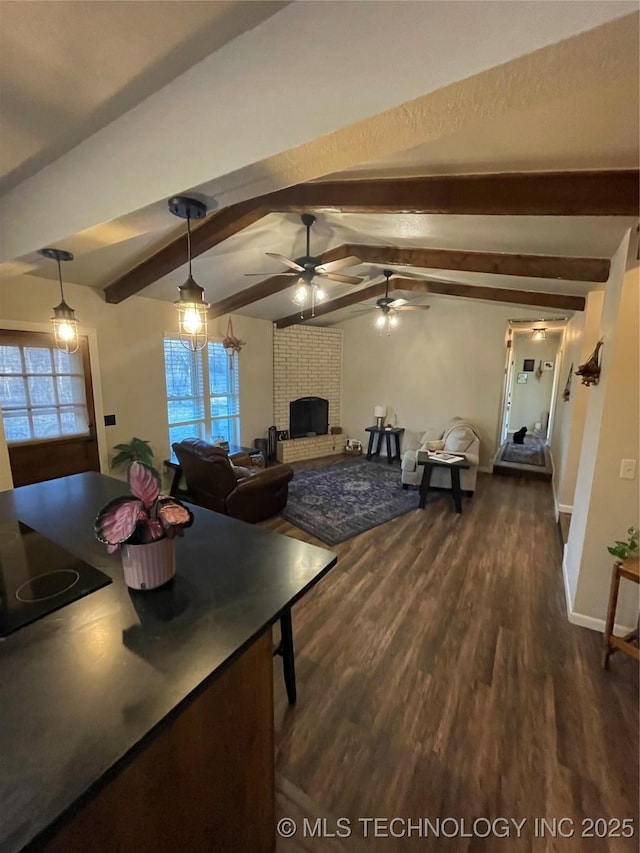 dining area featuring vaulted ceiling with beams, ceiling fan, dark wood-type flooring, and a brick fireplace