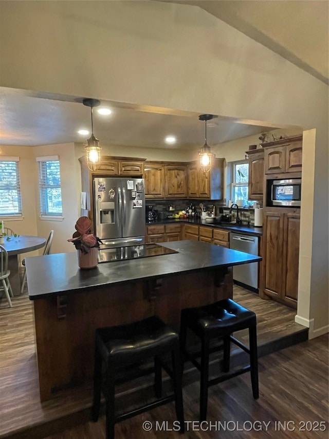 kitchen featuring dark hardwood / wood-style flooring, a kitchen island, pendant lighting, and appliances with stainless steel finishes