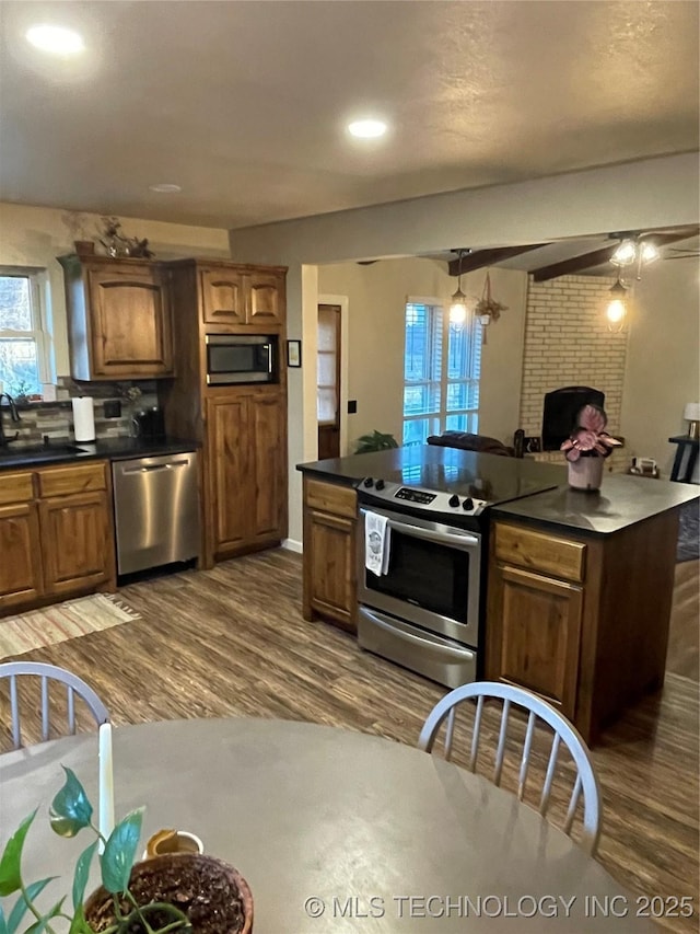 kitchen with stainless steel appliances, ceiling fan, dark wood-type flooring, sink, and a fireplace