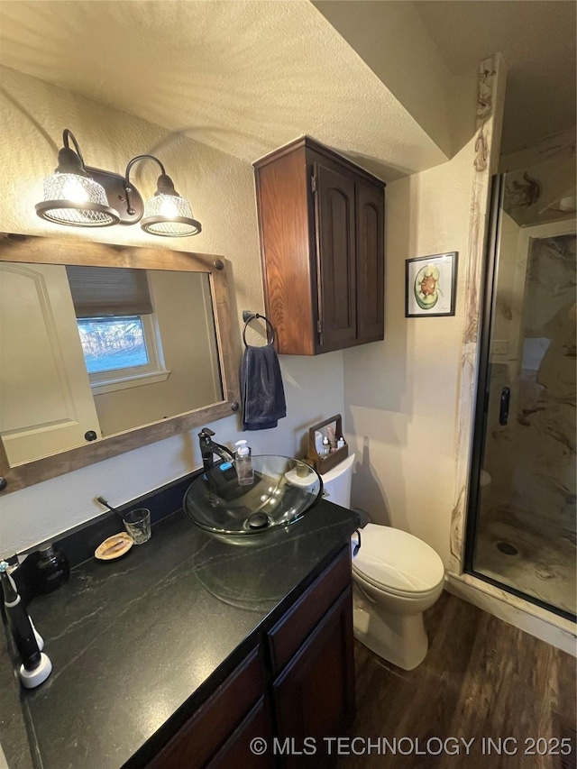 bathroom featuring vanity, hardwood / wood-style flooring, toilet, a textured ceiling, and an enclosed shower