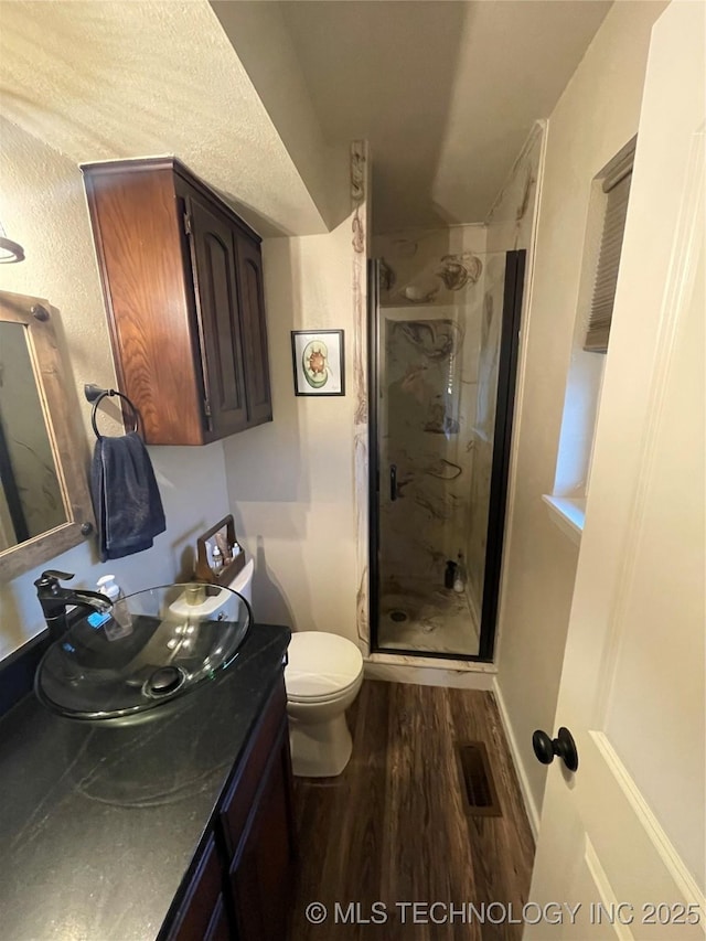 bathroom with hardwood / wood-style flooring, vanity, toilet, and an enclosed shower