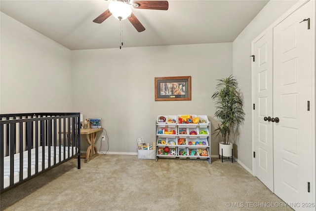 bedroom with carpet flooring, ceiling fan, and a crib