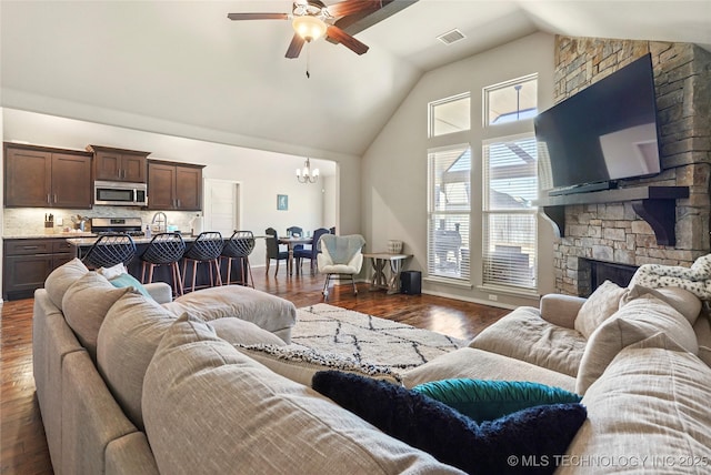 living room featuring a fireplace, ceiling fan with notable chandelier, dark hardwood / wood-style floors, and vaulted ceiling