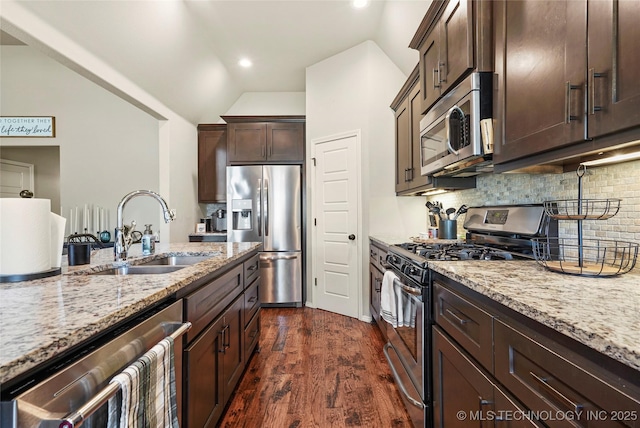 kitchen with dark wood-type flooring, sink, tasteful backsplash, light stone counters, and stainless steel appliances