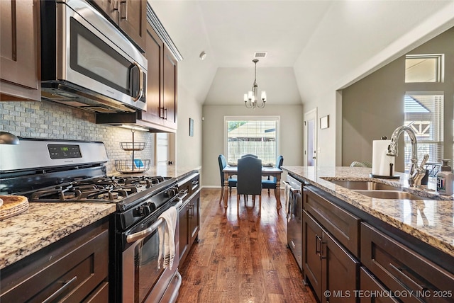 kitchen featuring light stone countertops, appliances with stainless steel finishes, sink, an inviting chandelier, and lofted ceiling