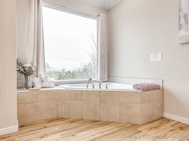 bathroom featuring hardwood / wood-style floors and a relaxing tiled tub