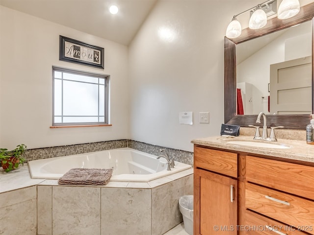 bathroom featuring vanity, tiled bath, and lofted ceiling