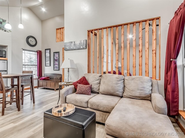 living room featuring high vaulted ceiling and light wood-type flooring