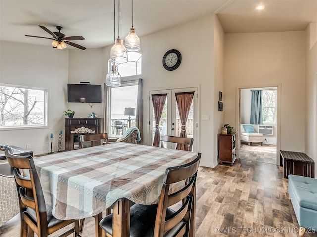 dining room featuring ceiling fan, french doors, a high ceiling, cooling unit, and light wood-type flooring