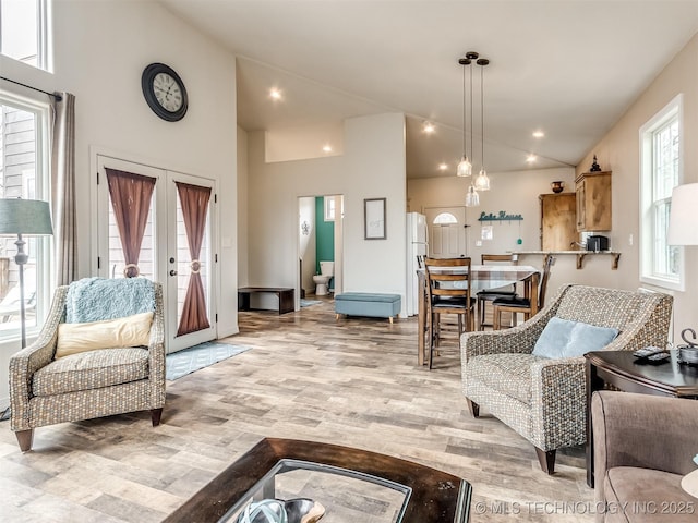 living room with french doors, high vaulted ceiling, and light hardwood / wood-style flooring