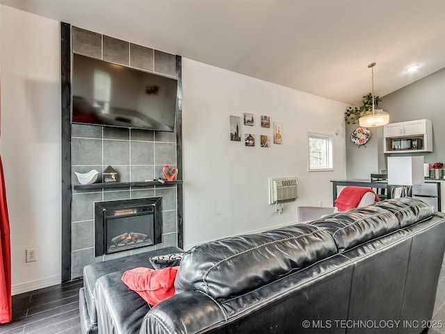 living room featuring a wall mounted AC, lofted ceiling, and a tiled fireplace