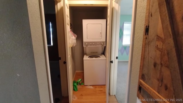 hall featuring stacked washing maching and dryer and light hardwood / wood-style floors