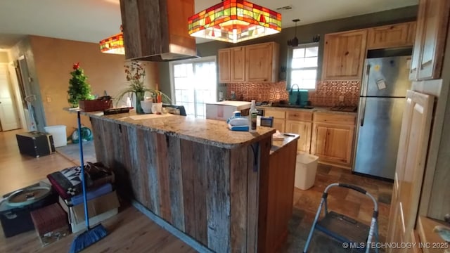 kitchen with decorative backsplash, sink, pendant lighting, hardwood / wood-style flooring, and stainless steel refrigerator