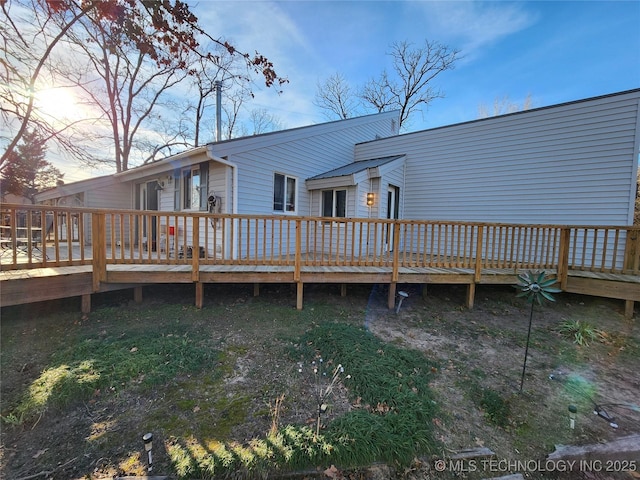 back house at dusk featuring a deck