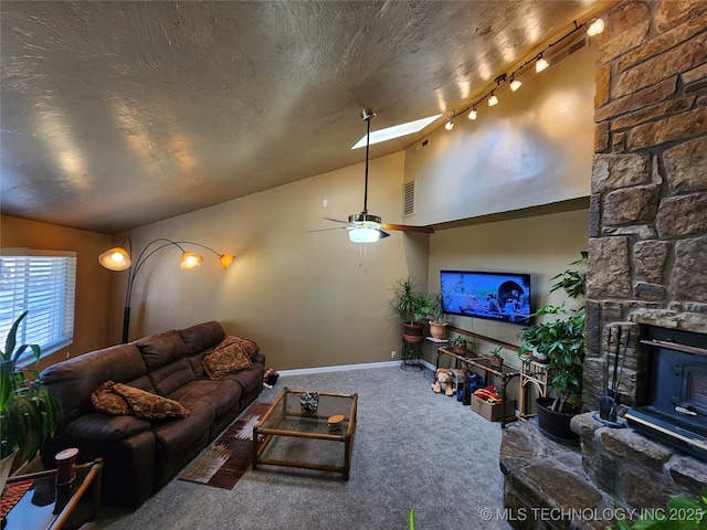 carpeted living room featuring high vaulted ceiling, a textured ceiling, a wood stove, track lighting, and ceiling fan