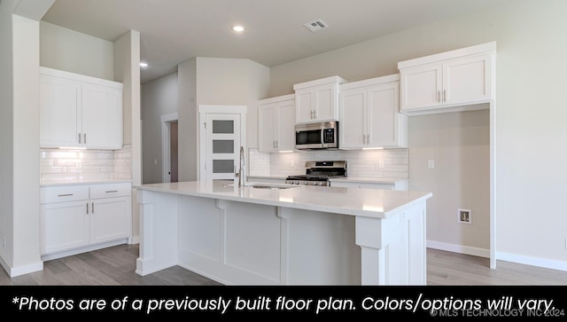 kitchen featuring white cabinets, appliances with stainless steel finishes, a kitchen island with sink, and sink