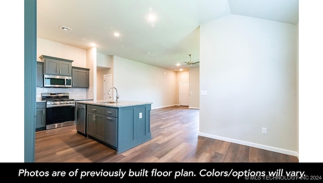 kitchen with decorative backsplash, stainless steel appliances, a kitchen island with sink, dark wood-type flooring, and sink