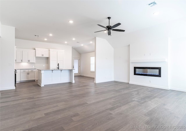 unfurnished living room featuring ceiling fan, lofted ceiling, sink, and light wood-type flooring