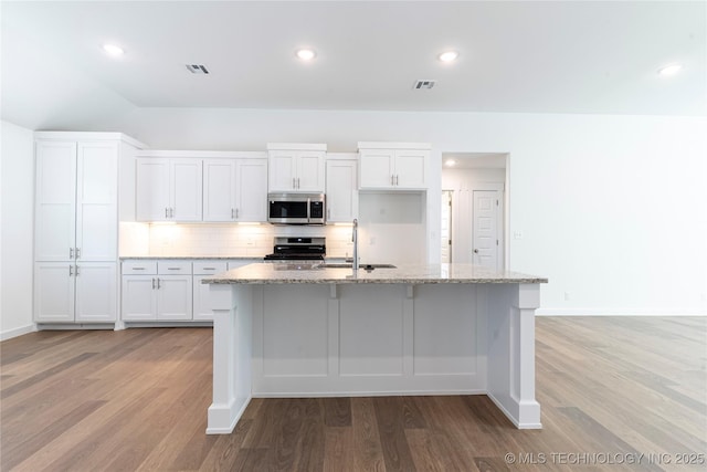 kitchen featuring appliances with stainless steel finishes, white cabinetry, an island with sink, sink, and light stone counters