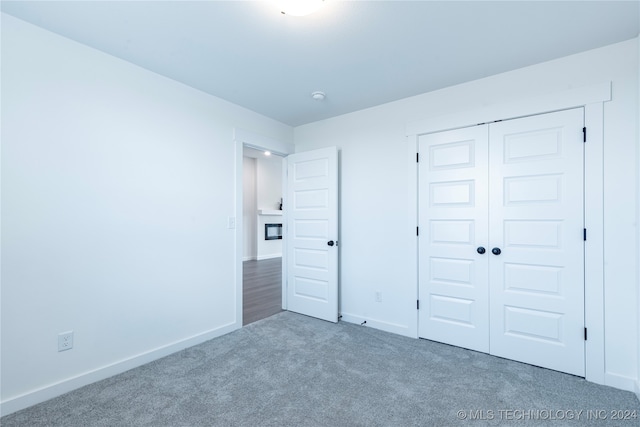 unfurnished bedroom with a closet and dark colored carpet