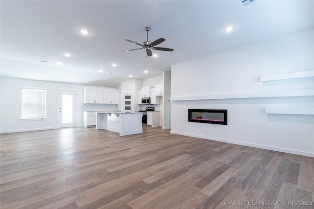 unfurnished living room with ceiling fan and light wood-type flooring