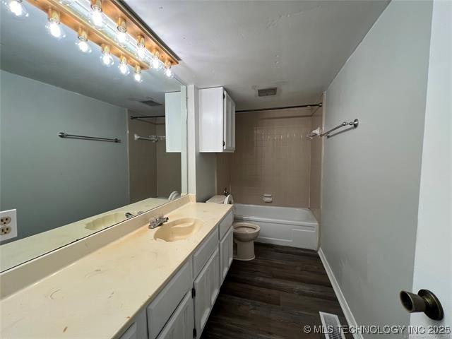 full bathroom featuring hardwood / wood-style floors, vanity, toilet, and tiled shower / bath combo