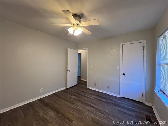 unfurnished bedroom featuring ceiling fan and dark hardwood / wood-style flooring