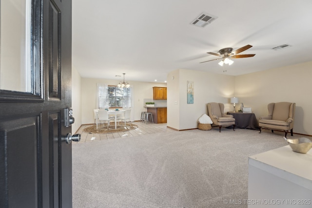 carpeted living room featuring ceiling fan with notable chandelier