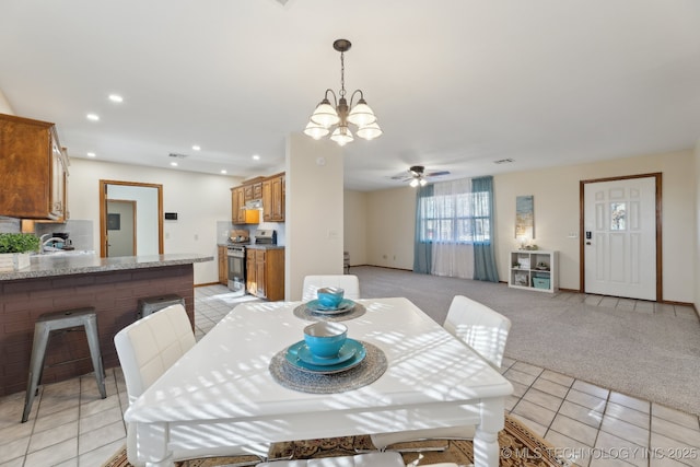 carpeted dining area featuring ceiling fan with notable chandelier