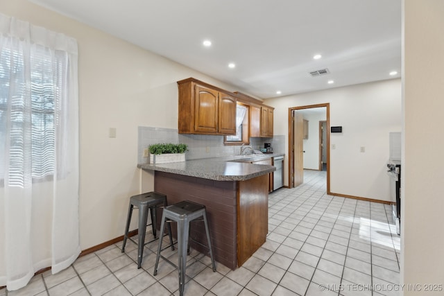 kitchen with stainless steel appliances, kitchen peninsula, a kitchen bar, sink, and tasteful backsplash