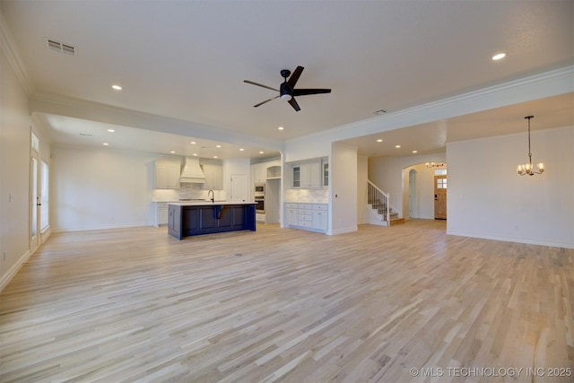 unfurnished living room featuring light hardwood / wood-style flooring, ceiling fan with notable chandelier, and ornamental molding