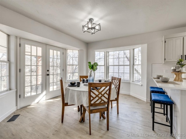 dining area featuring a textured ceiling, a notable chandelier, and light wood-type flooring