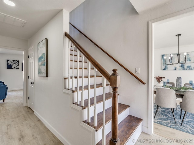 staircase featuring a chandelier and wood-type flooring