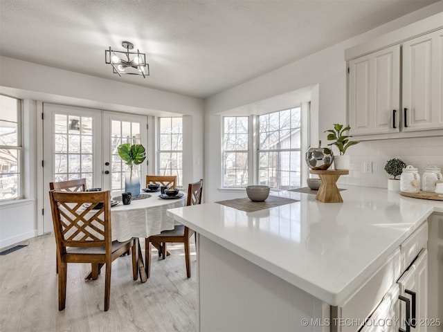 dining room featuring light hardwood / wood-style floors, an inviting chandelier, and french doors