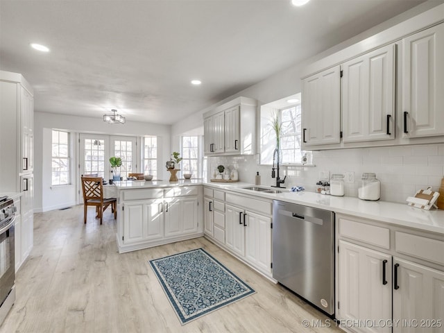 kitchen featuring kitchen peninsula, sink, white cabinets, and stainless steel appliances