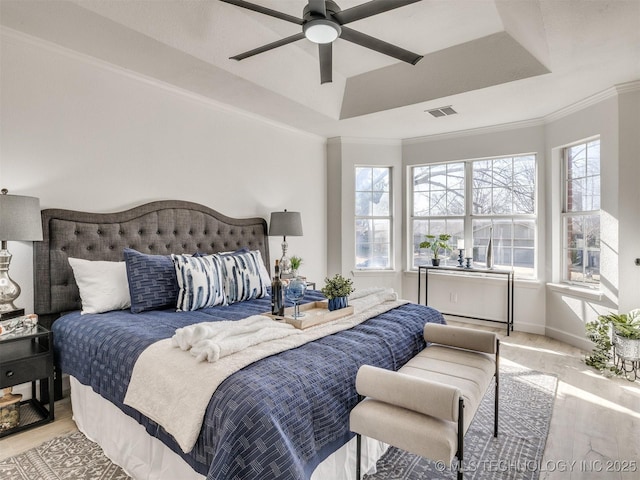 bedroom with a raised ceiling, multiple windows, and ceiling fan