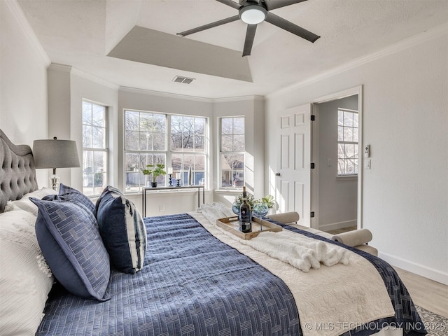 bedroom featuring ceiling fan, wood-type flooring, crown molding, and a tray ceiling