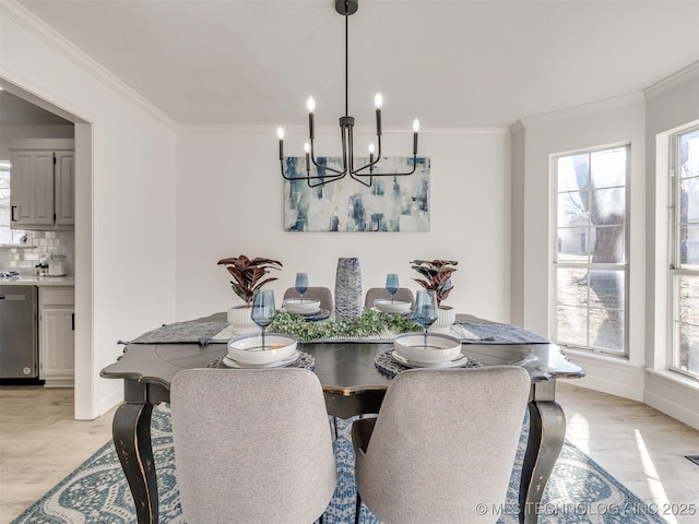 dining space featuring a healthy amount of sunlight, light wood-type flooring, crown molding, and a chandelier