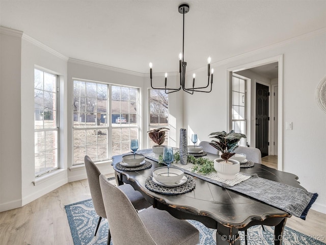 dining room with ornamental molding, light wood-type flooring, a healthy amount of sunlight, and a notable chandelier