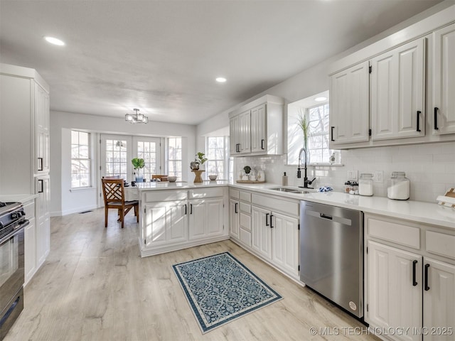 kitchen featuring dishwasher, white cabinetry, black range, and sink