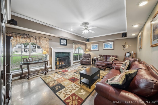 living room featuring ceiling fan, crown molding, a tile fireplace, and concrete floors