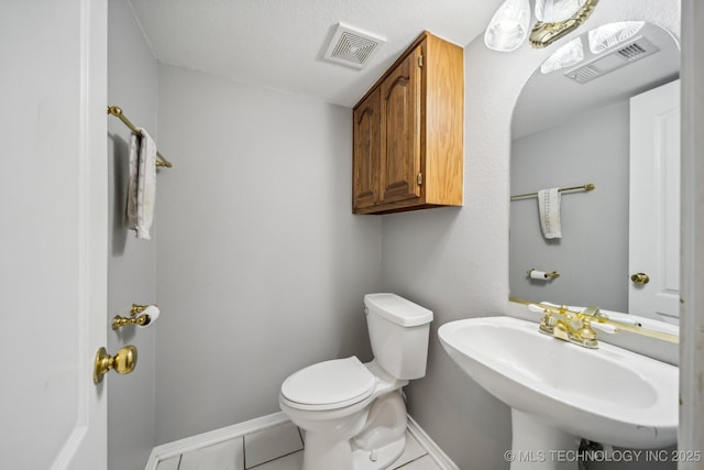 bathroom with toilet, tile patterned flooring, and sink