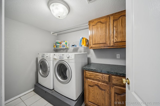 washroom featuring cabinets, independent washer and dryer, a textured ceiling, and light tile patterned floors