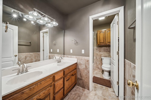 bathroom with tile patterned flooring, vanity, toilet, and tile walls