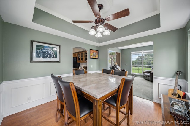 dining space with hardwood / wood-style floors, ceiling fan, and a raised ceiling