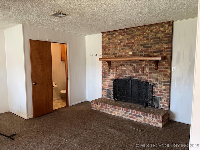 unfurnished living room featuring wooden walls, dark carpet, a textured ceiling, and a brick fireplace